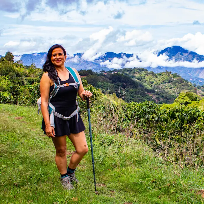 Senderista sonriente posando con su equipo de montaña frente al paisaje de Copalchí Vertical.